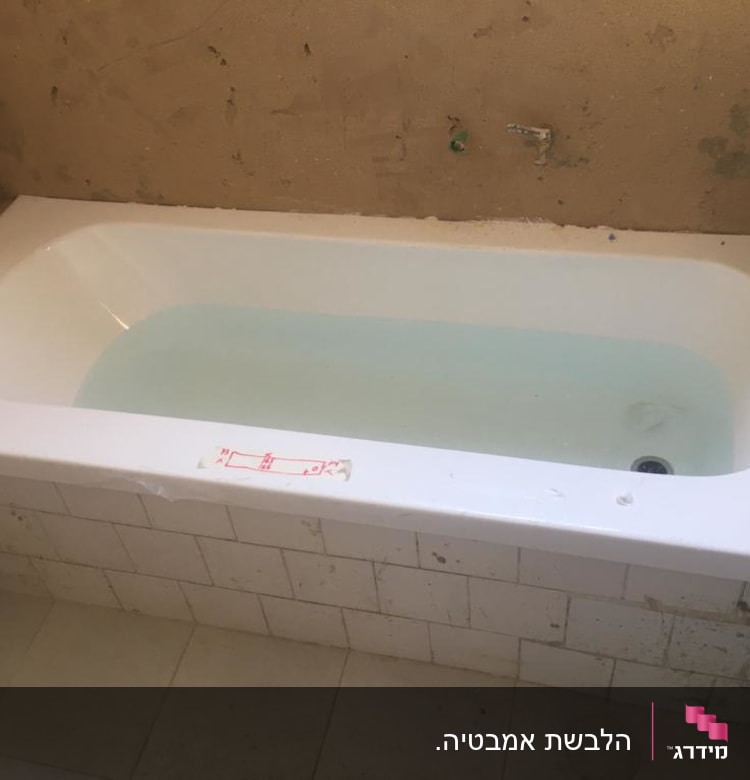 אמבטיה עם מים, קירות לא גמורים, אריחים לבנים